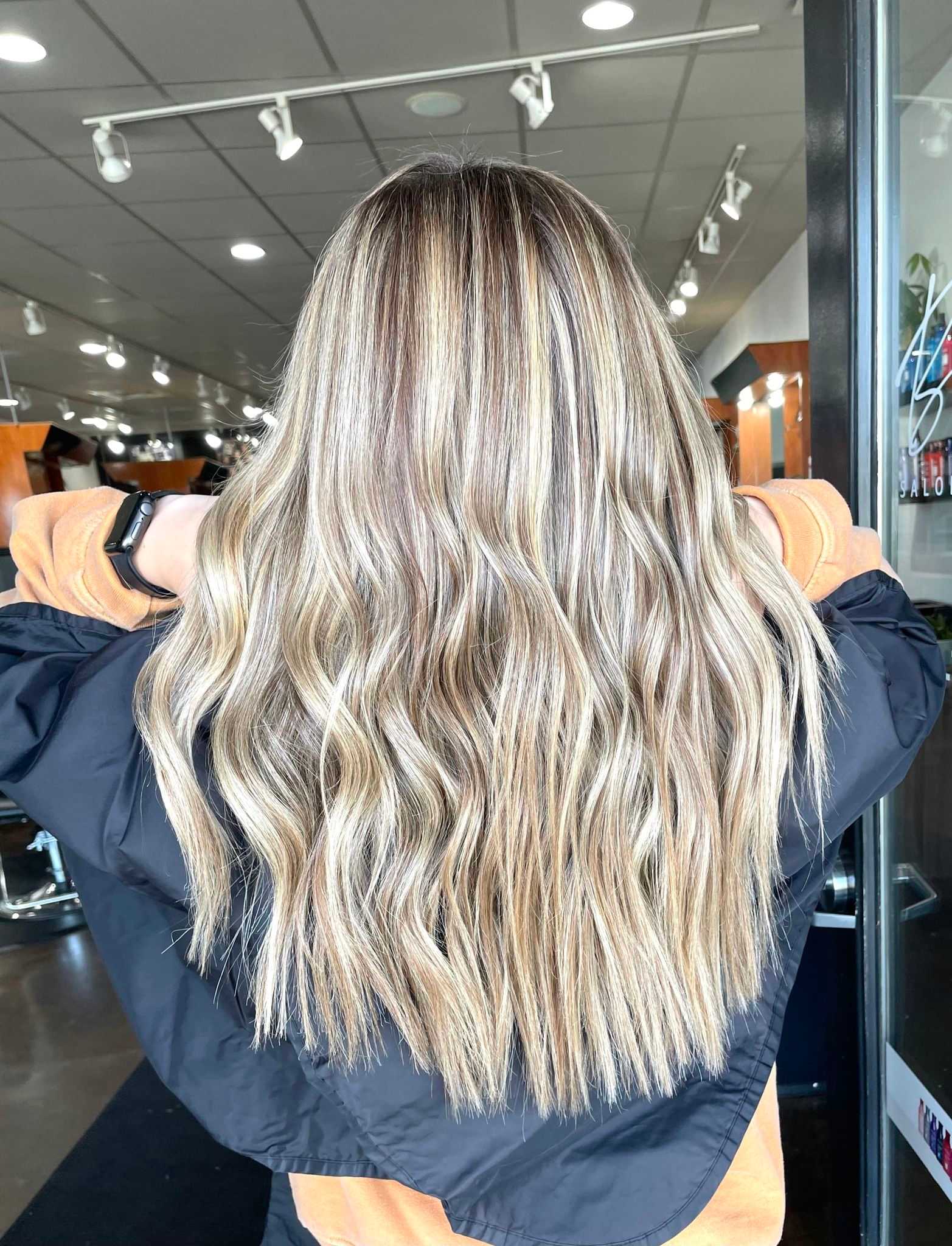 Long, wavy blonde hair with highlights displayed in a salon setting.