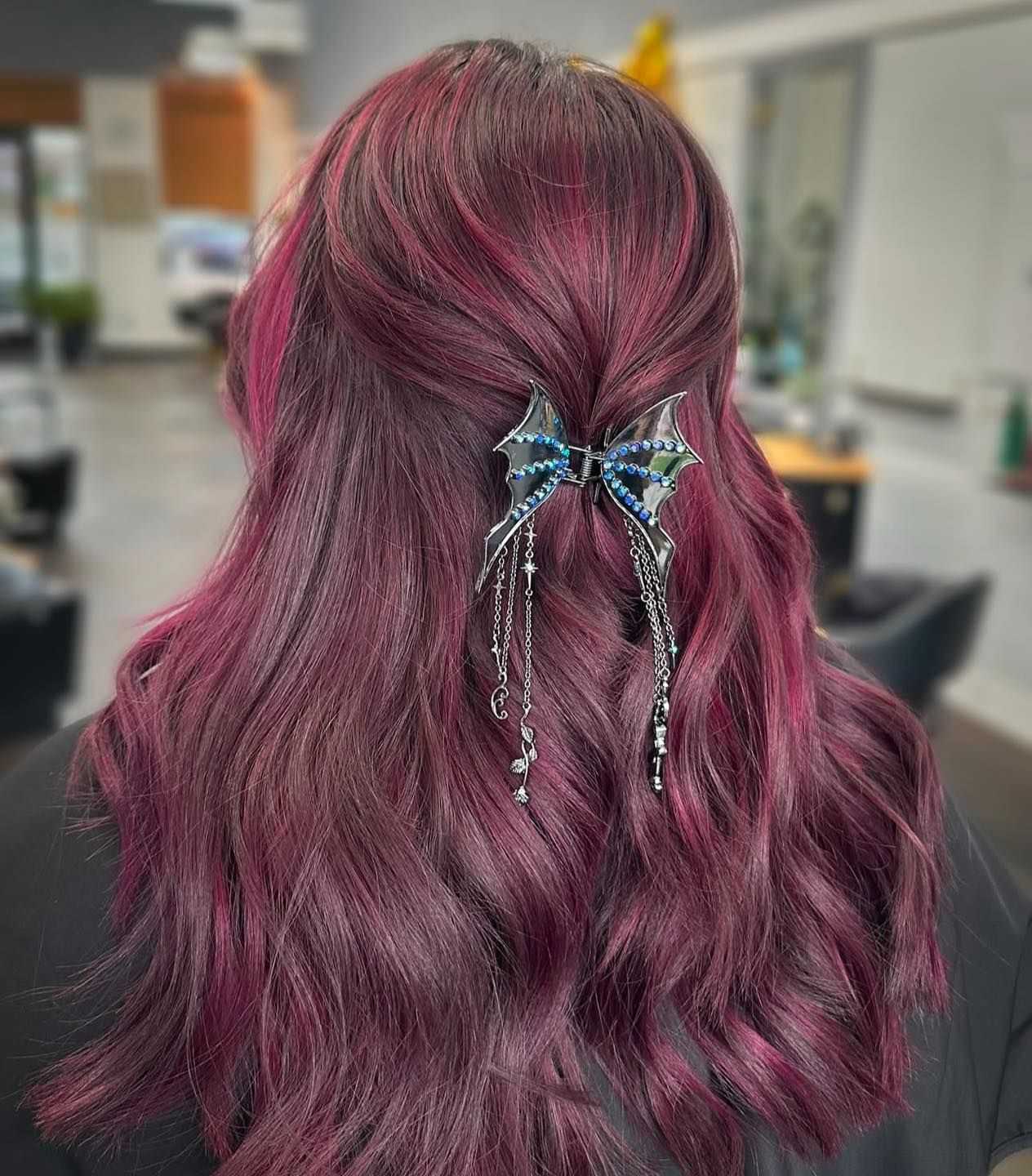Hair with vibrant pink and purple hues styled with a bat-shaped hair accessory.