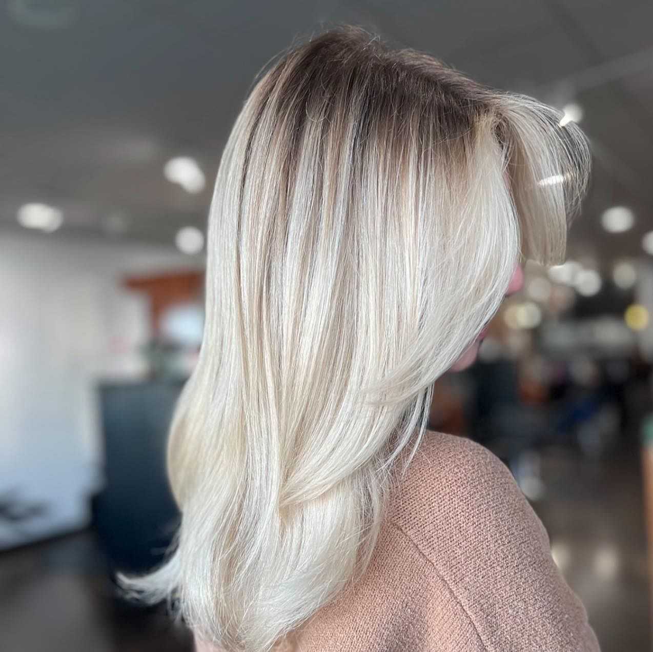Blonde hair styled with soft layers in a salon setting.