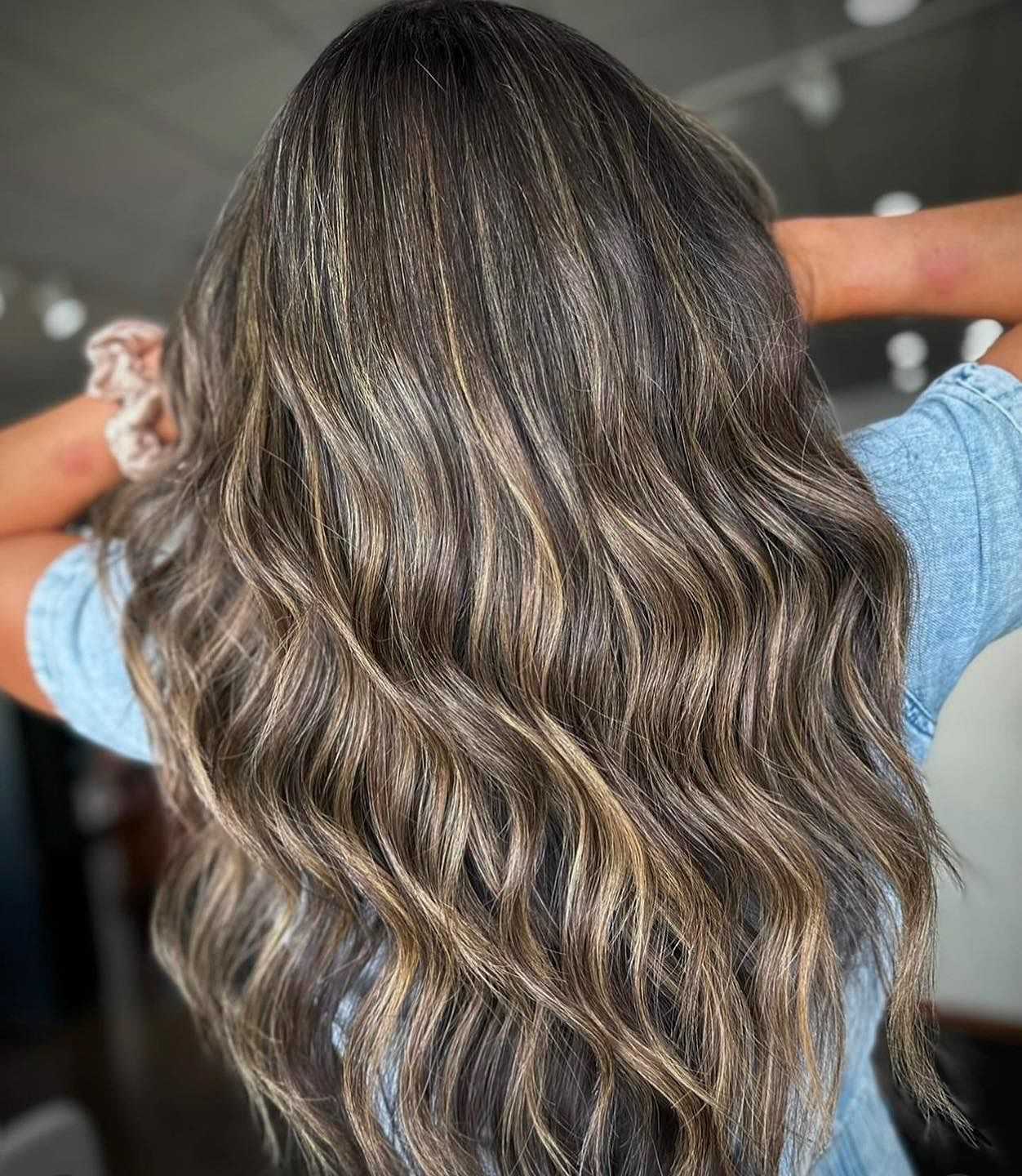 Wavy, long brown hair with highlights, shown from the back in a well-lit room.